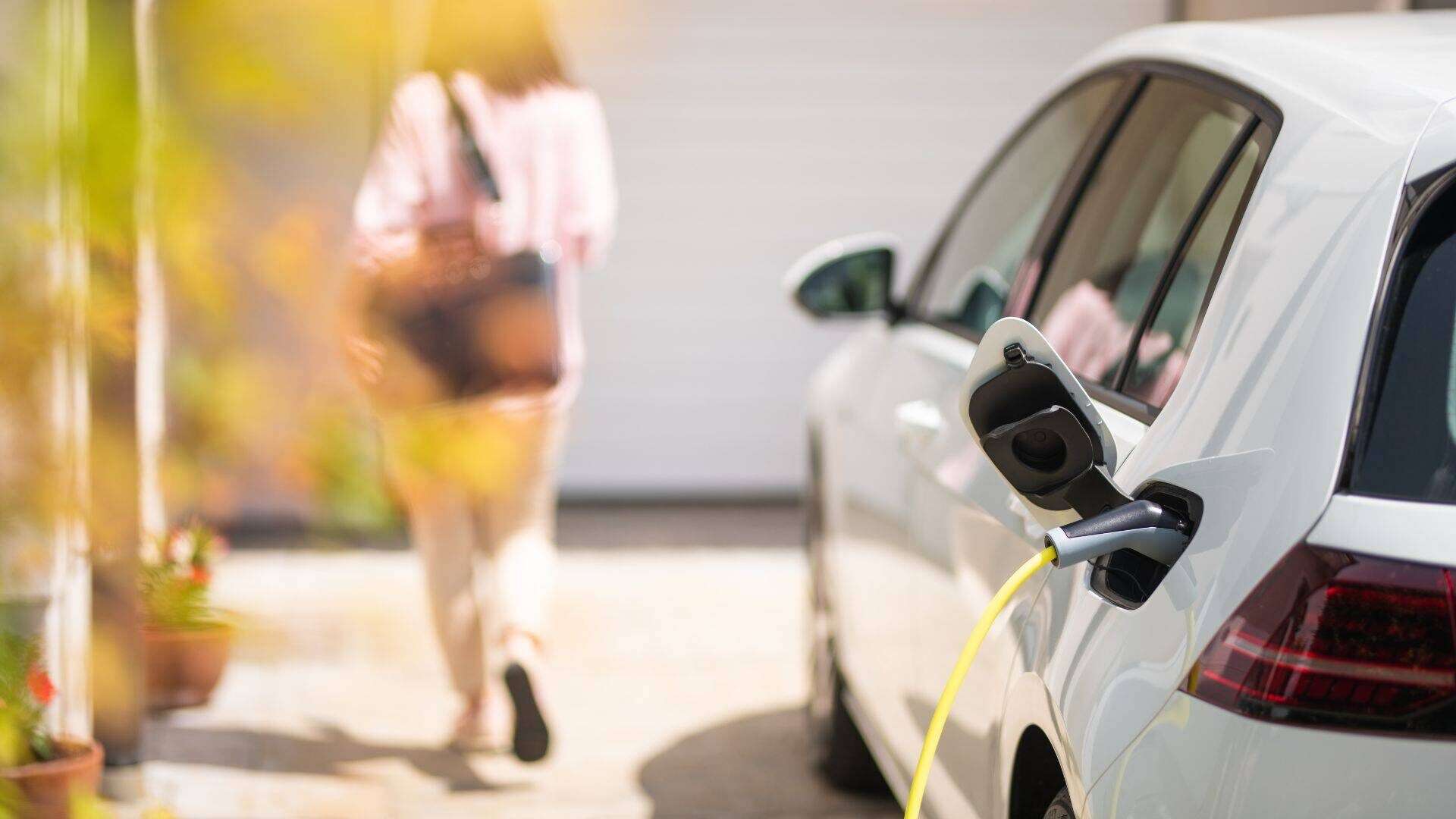 Image of a electric vehicle charging station with a woman walking away from the car