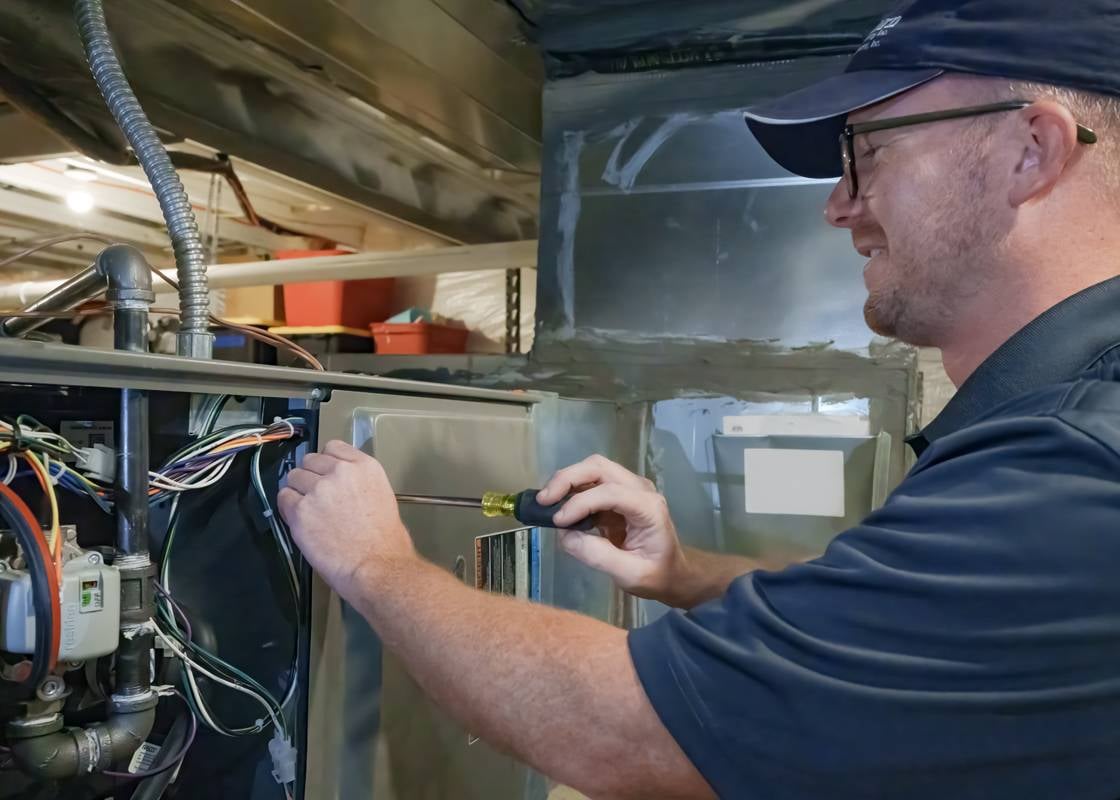 Elkhorn HVAC technician working on a central air conditioning unit, performing maintenance and repair.