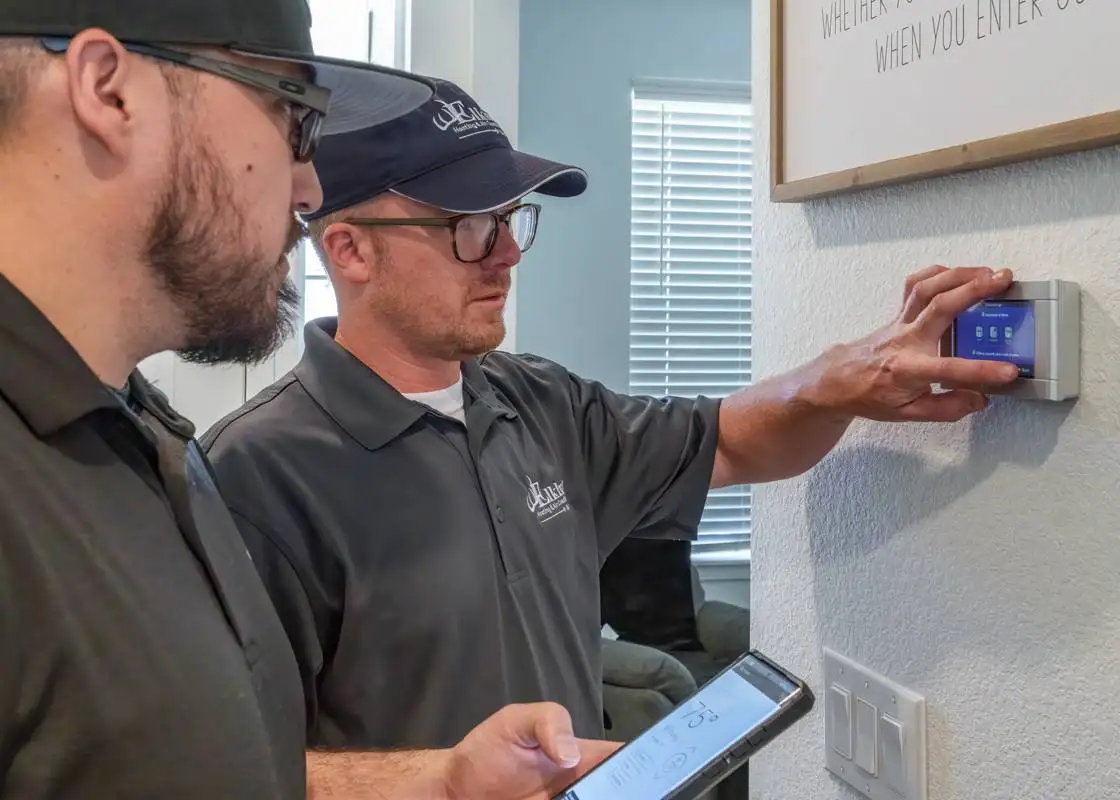 Technician servicing a thermostat for AC controls in Denver home.