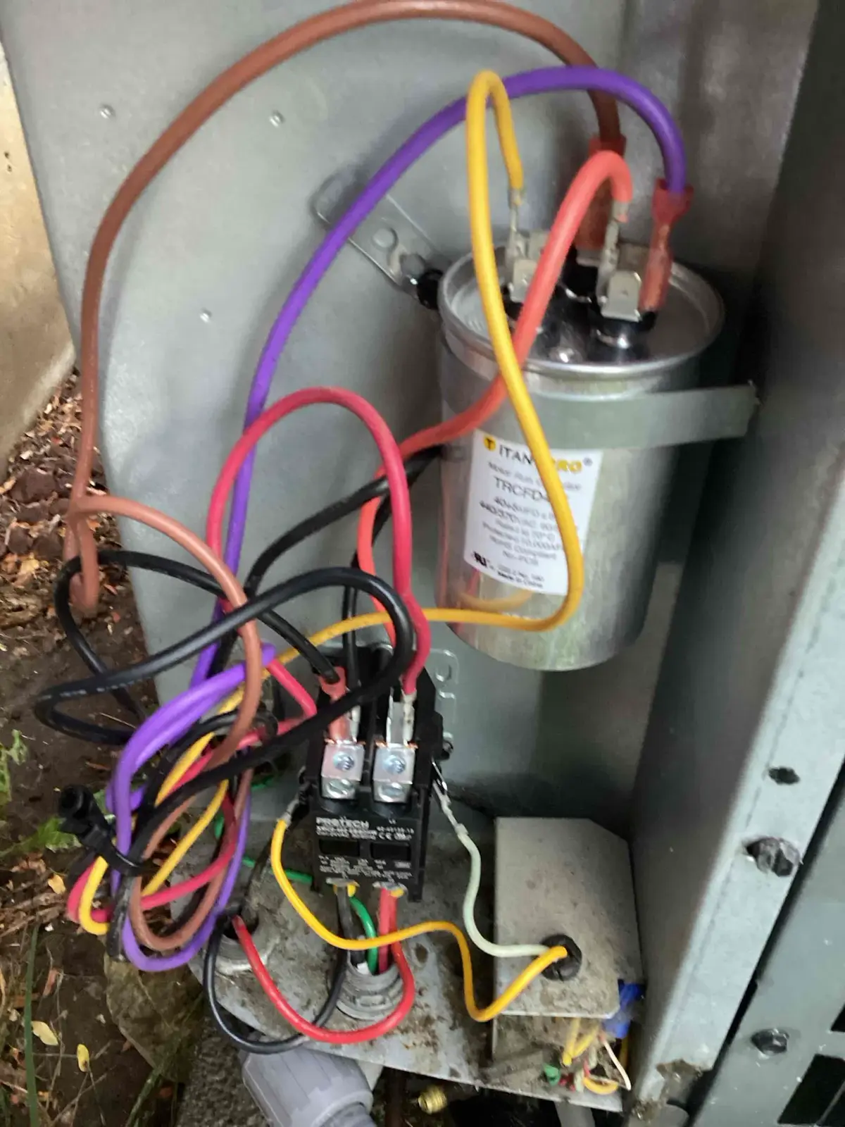 New capacitor and contactor installed inside a Denver outdoor AC unit after electrical component replacement.