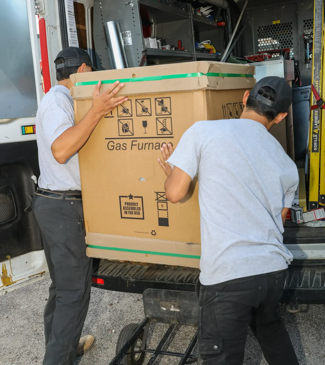 Elkhorn technicians guide a packaged furnace up a ramp into a work van