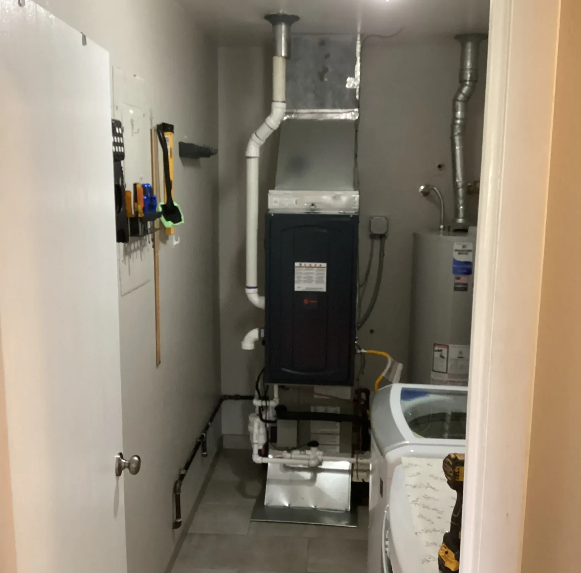 Residential furnace and water heater installed in a narrow utility room beside a washing machine