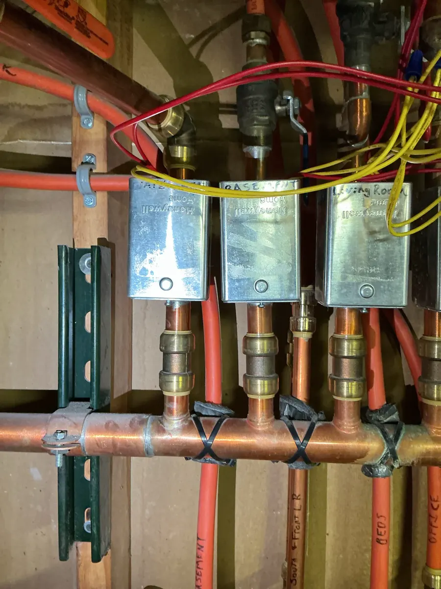 Zone valve power heads and wiring on copper boiler heating pipes in a Denver home.