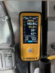 Fieldpiece combustion analyzer displaying readings beside a furnace during heat exchanger service in Littleton.