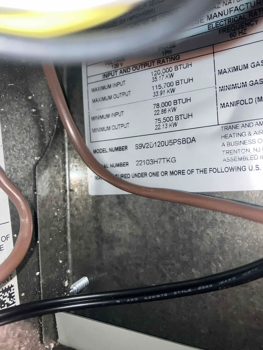 Furnace equipment label with model and heating-capacity information inside a Highlands Ranch furnace.